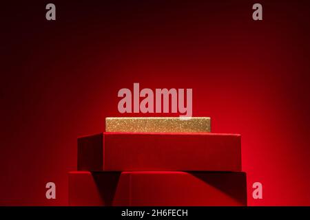 Majestic empty red podium made of gift boxes Red background .Pedestal, showcase for products and cosmetics. Chinese New Year concept Copy Space, Verti Stock Photo