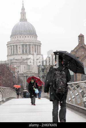 Commuters make their way across the millennium bridge in the snow in London this morning. Stock Photo