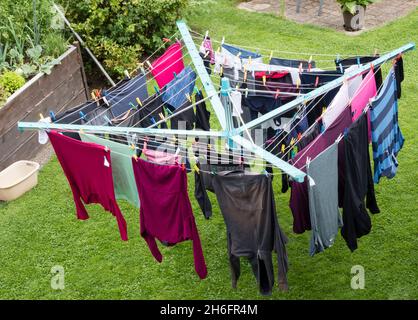 Wet laundry is hanging on a rotary clothes dryer outside in the garden of a residential home in Germany Stock Photo