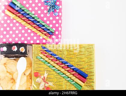 Glittering Golden Yellow, Red, Blue And Green Candles Decorated On Gift Box Wrapped In Pink Paper Accompanied With Tasty Food Crispy Wafers Chips And Stock Photo