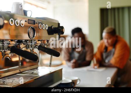 Selective focus on coffee machine shot young man and woman starting workday in small cafe with creating menu Stock Photo