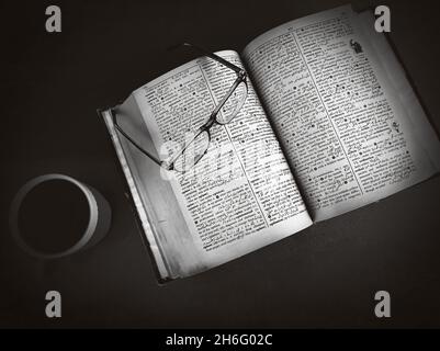 Black And White Studying and Reading concept background with black coffee and glasses on the dark table. Old and Antique Style Reading Background with Stock Photo
