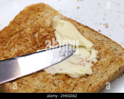 close up of knife spreading magarine onto wholemeal toast Stock Photo