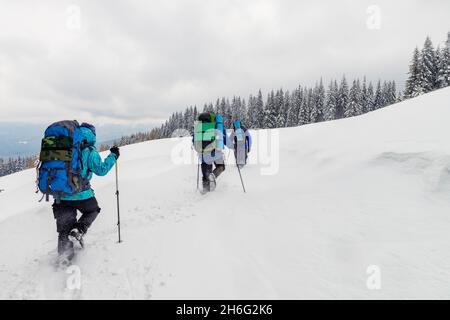 Group of hikers explore the wild mountain terrain in the deep snow. Dangerous winter sport Stock Photo