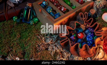 Image of a leather dice bag, wooden dice tray, and potions on green and gray moss. Stock Photo
