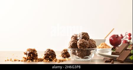 Preparing homemade chocolate balls with almond chips on table decorated for Christmas white isolated background. Front view. Horizontal composition. Stock Photo