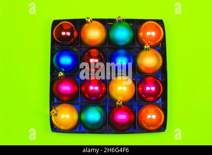 Box of multicolor Christmas balls on green background Stock Photo