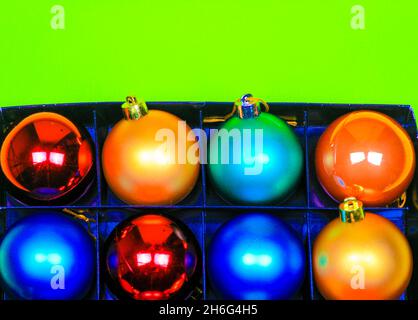 Box of multicolor Christmas balls on green background Stock Photo