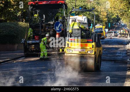 Workers using road roller in street resurfacing works in London England United Kingdom UK Stock Photo