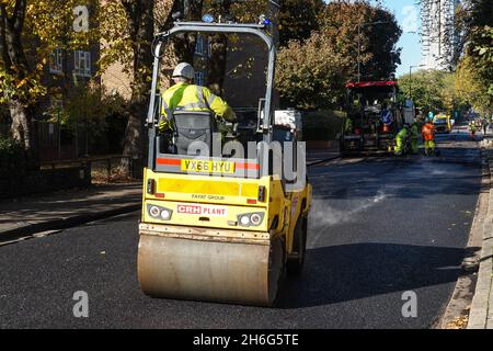 Workers using road roller in street resurfacing works in London England United Kingdom UK Stock Photo