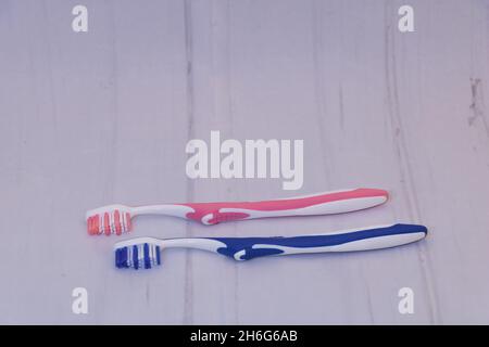 Two toothbrushes - one blue and one pink with on gray surface with copy space Stock Photo