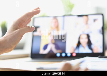 Female hand on background of tablet with video call from employees Stock Photo