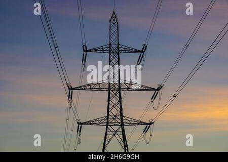 Electricity pylon and colourful sunset sky Stock Photo