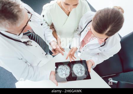Team of doctors and nurses in meeting using a tablet computer Stock Photo