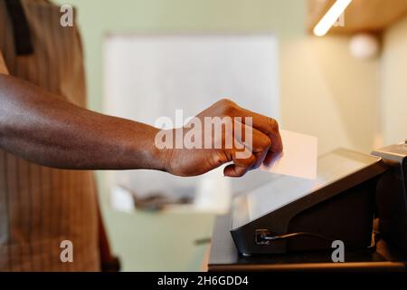 Horizontal side view shot of unrecognizable cafe worker adding information about order using modern cash register machine with touchscreen Stock Photo