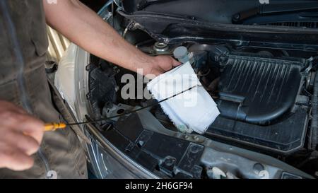 Auto mechanic wipes the dipstick to check the oil level in the engine. Stock Photo