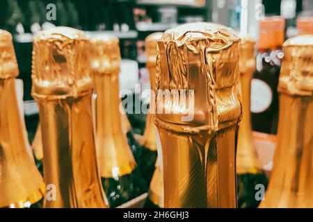 Lots of champagne bottles in store. Sale of alcoholic beverages before the holiday. Close up of bottlenecks. Stock Photo