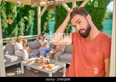 A man in red shirt standing with a thoughtful look Stock Photo