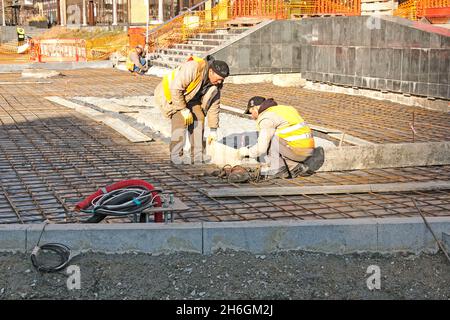 Dnepropetrovsk, Ukraine - 11.14.2021: Workers are laying a mesh of reinforcement for paving slabs. The basis for concreting the sidewalk. Stock Photo