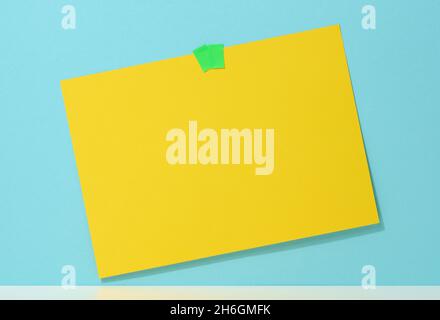 blank rectangular yellow sheet of paper glued on a blue background. Place for an inscription, announcement Stock Photo