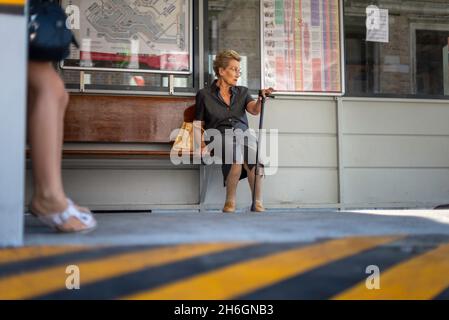 Elderly woman with a cane waits for the vaporetto to arrive Stock Photo