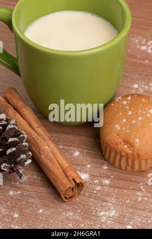 green cup with milk next to a cupcakes on a wooden table decorated with powdered sugar and cinnamon, food and drink in studio, sweet dessert Stock Photo
