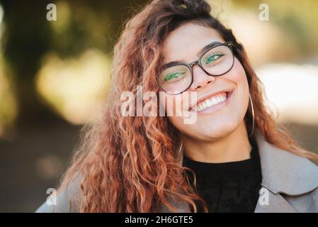 beautiful woman and beautiful look, holds her black glasses with her hands outdoors Stock Photo