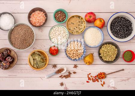 Set of different and beautiful bowls filled with raw products. Bell pepper seed, black beans, brown lentils, ñoras, bay leaf, cayenne in spoon, parsle Stock Photo