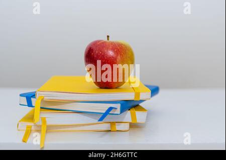 Books on table, yellow and blue hardcover textbooks with an apple. Copy space. Stock Photo