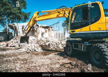 Demolition of building. Process of dismantling of house. Excavator breaks old building. Stock Photo