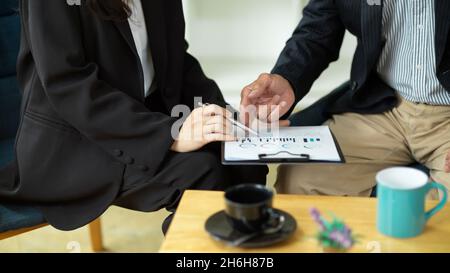 Cropped image of Aged businessman reading his business financial plans report with female consultant. Stock Photo