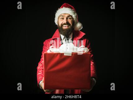 Surprised santa with christmas gift isolated on black. Funny Santa man in winter clothes wishes merry Christmas. Stock Photo