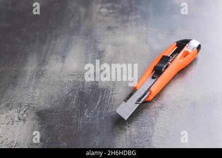 Plastic orange utility knife on table. Stock Photo