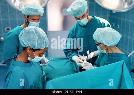 Surgeons team working on patient in surgical operating room. Healthcare emergency people concept Stock Photo