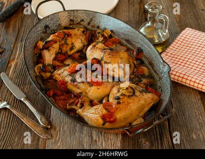 rustic chicken dish with vegetables served in a old fashioned roasting pan on wooden table Stock Photo