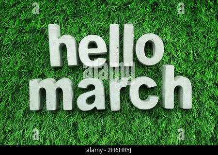 Hello March made from concrete alphabet top view on green grass Stock Photo