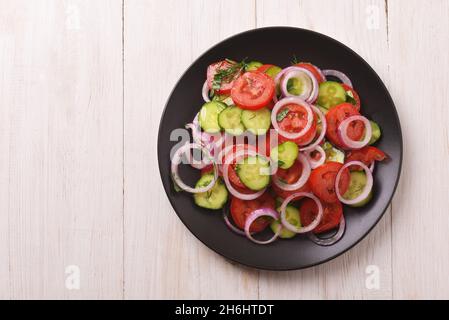 Top view of fresh tomatoes cucumber vegetable salad on white wooden table Stock Photo