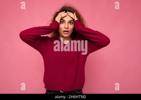 Portrait of young emotional surprised, amazed, shocked beautiful attractive brunette curly woman with sincere emotions wearing stylish pink pullover Stock Photo