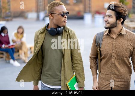 Male students walk and talk at university campus Stock Photo