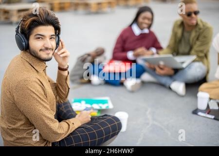 Indian man sit on asphalt and look at camera Stock Photo