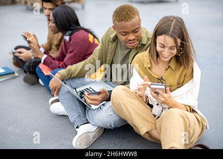 Students sitting and using gadgets on asphalt Stock Photo