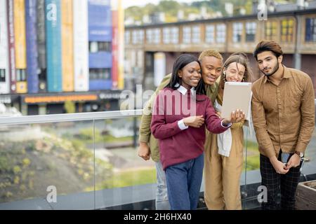 Multiracial students watch some on digital tablet Stock Photo