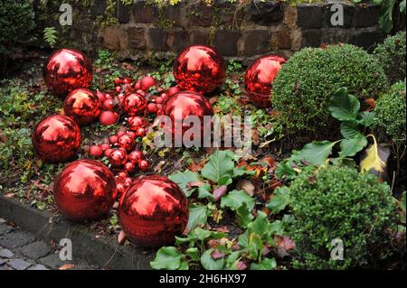 Christmas decoration in a garden. Red balls in a flower bed Stock Photo