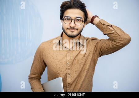 Young indian man with laptop looking at camera Stock Photo