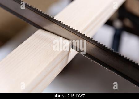 Hand saw cuts a wooden slat in the workshop. Close up, selective focus, and copy space Stock Photo
