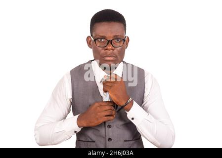 Serious young businessman wearing a gray suit vest with glasses adjusting his tie while looking at the camera Stock Photo