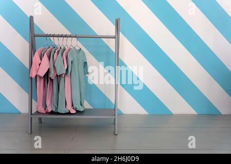 Childrens colorful clothes hang on a hanger in a store, copy space Stock Photo