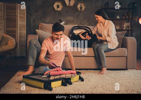 Photo of mom mommy dad daddy arrange family weekend abroad put clothes luggage kid daughter safety seat evening late room Stock Photo