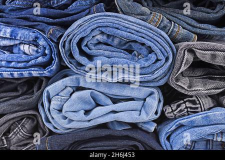 Different colored jeans pants rolled up in pile Stock Photo