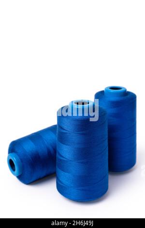 Threads of trendy electric blue on a white background. Side view of a bobbin of sewing thread. Vertical photo Stock Photo